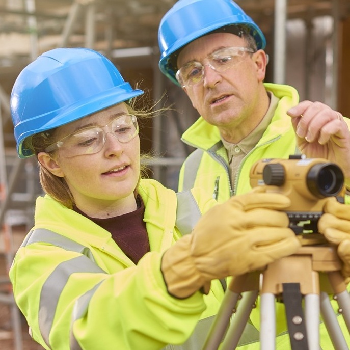 construction worker learning how to use a builder's level